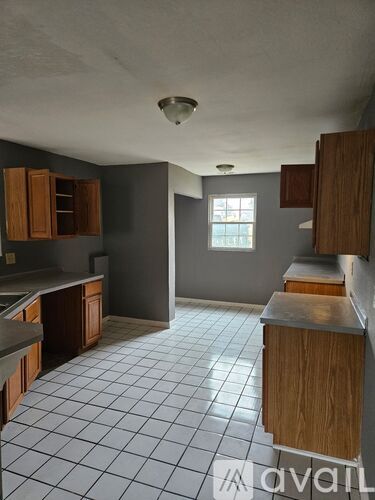 A kitchen with wooden cabinets and a tiled floor.