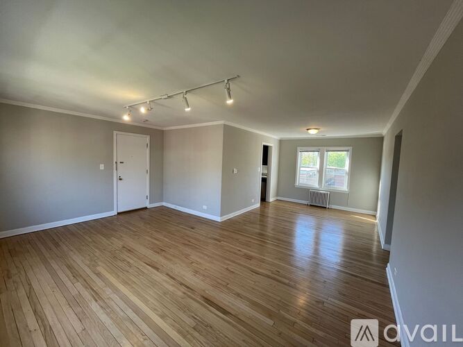 A room with wooden flooring and a window with blinds.