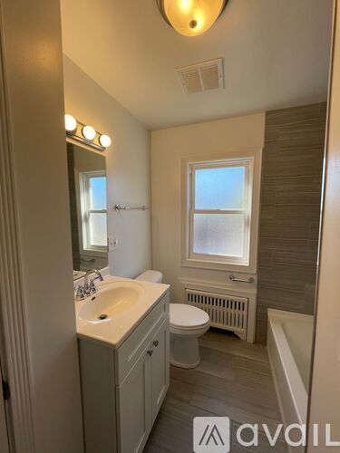 A bathroom with a sink, toilet, and window.
