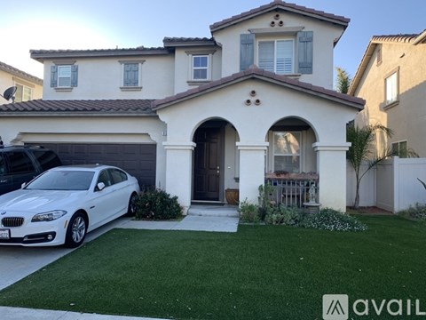 A white BMW car is parked in front of a two-story house.
