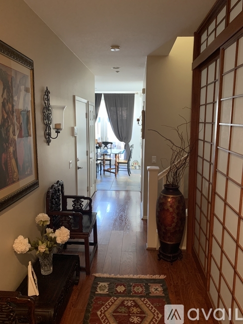 A hallway with a rug and a vase on the floor.