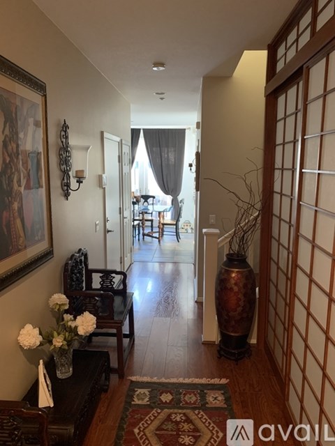 A hallway with a rug and a vase on the floor.