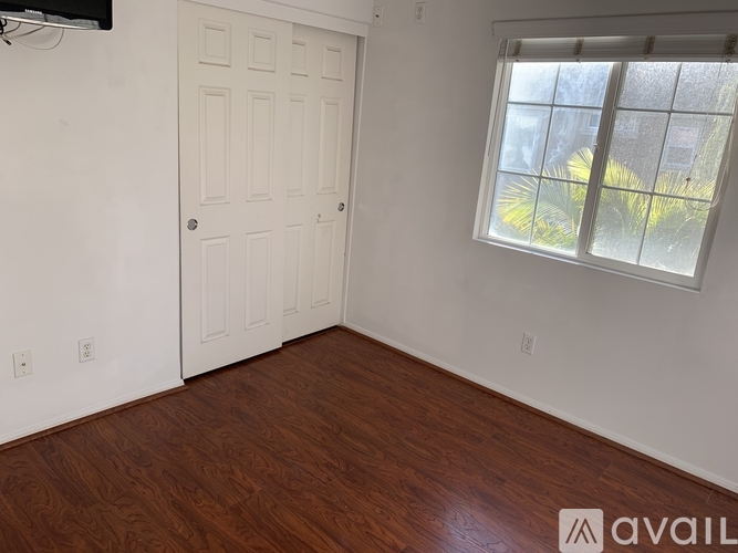A room with a white door and a window with a view of a building outside.