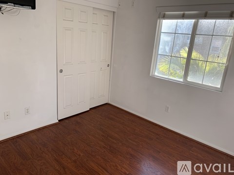 A room with a white door and a window with a view of a building outside.