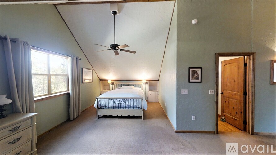 A bedroom with a bed, dresser, and window.