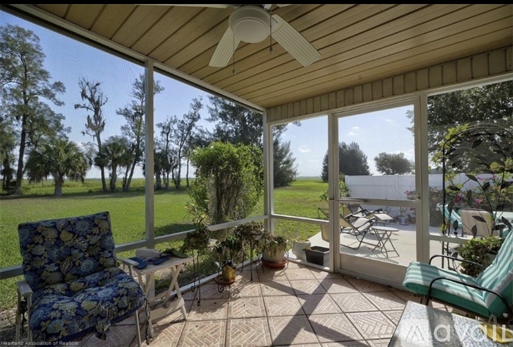 A screened porch with a ceiling fan and a view of the backyard.