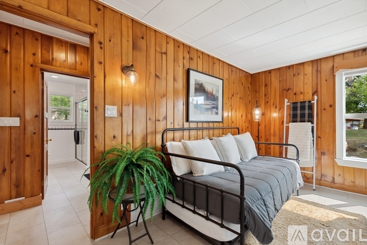 A bedroom with a bed, a plant, and a wooden wall.