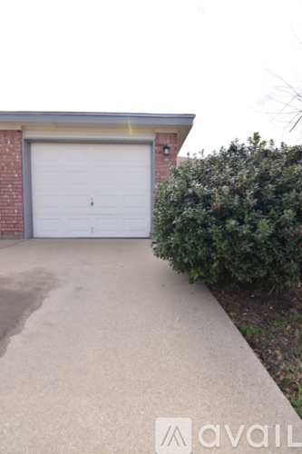 A garage door is closed and the driveway is concrete.