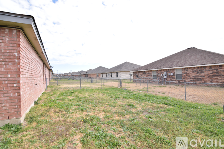 A grassy area in front of a brick building with a fence.