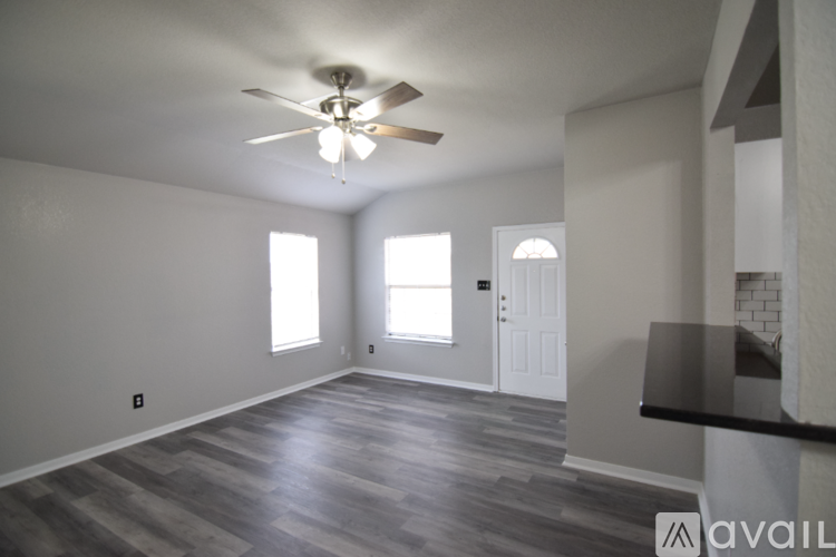 A spacious room with a ceiling fan and wooden flooring.