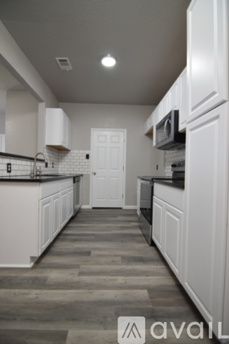 A kitchen with white cabinets and a black countertop.