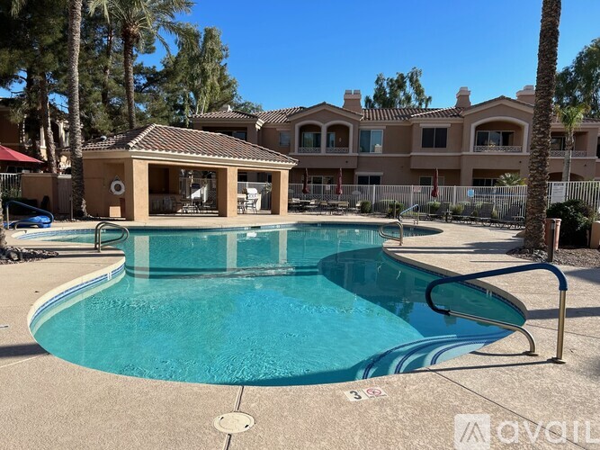 A swimming pool in front of a building with a pool house.