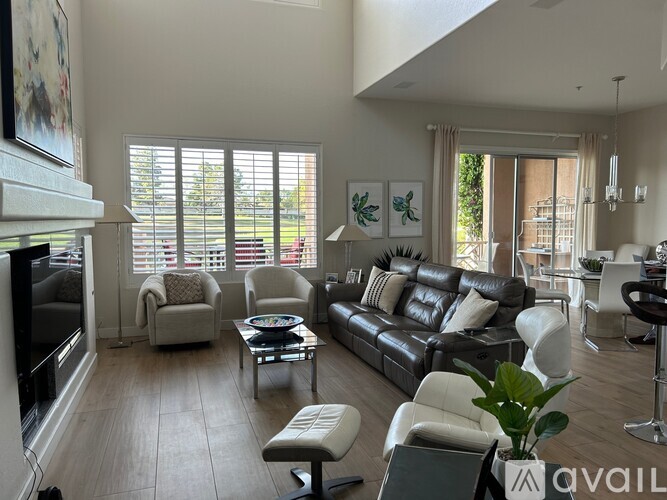A living room with a black leather couch and a fireplace.