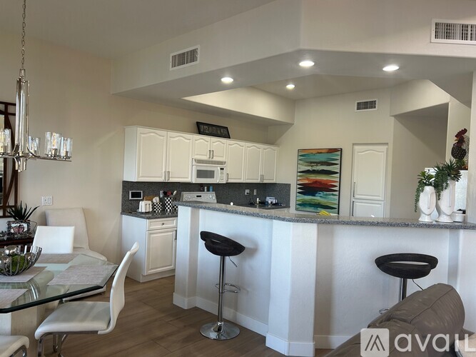 A modern kitchen with white cabinets and a glass table.