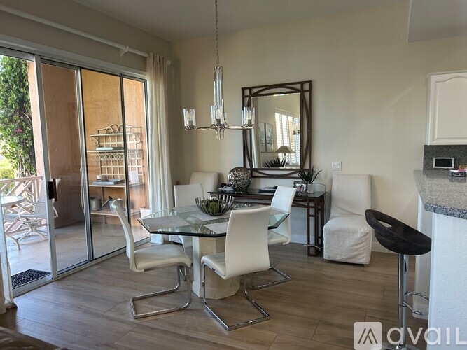 A modern dining room with a glass table and white chairs.