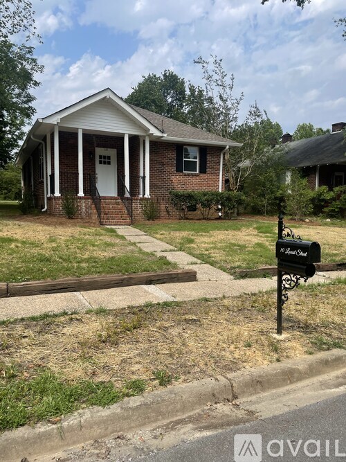 A small brick house with a white porch and a white door.