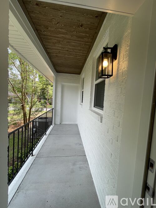 A brick patio with a black railing and a white porch.