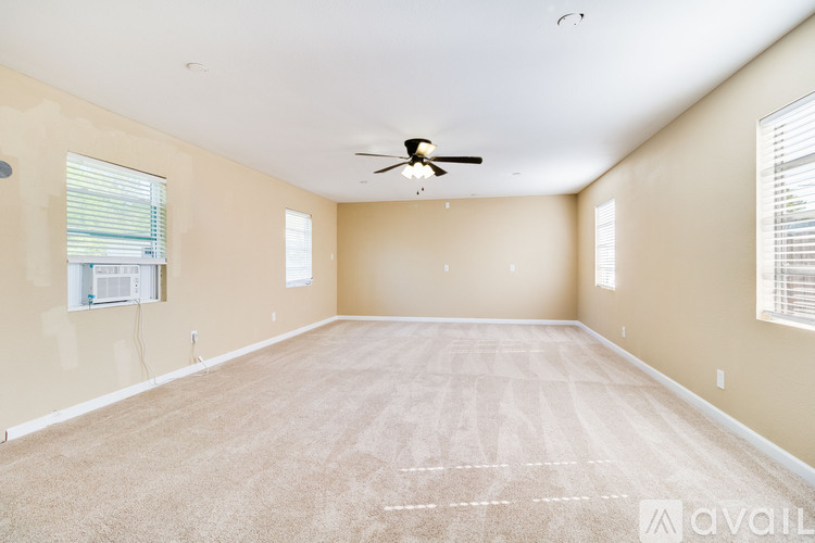 A spacious room with a ceiling fan and carpeted floor.