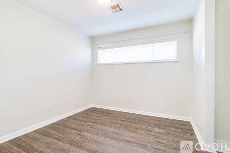 A room with a window and wooden flooring.