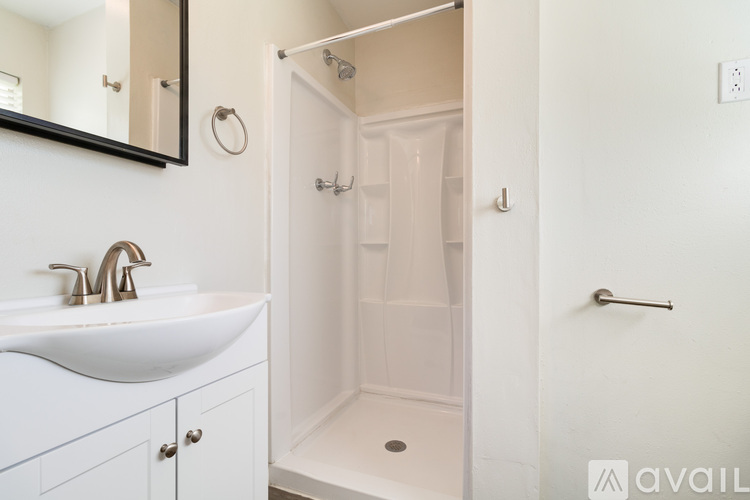 A white bathroom with a sink, mirror, and shower.