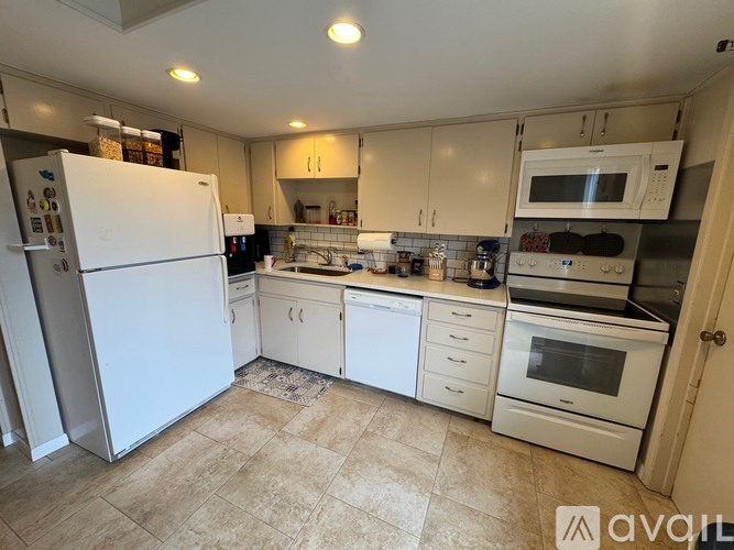 A kitchen with white appliances and cabinets.