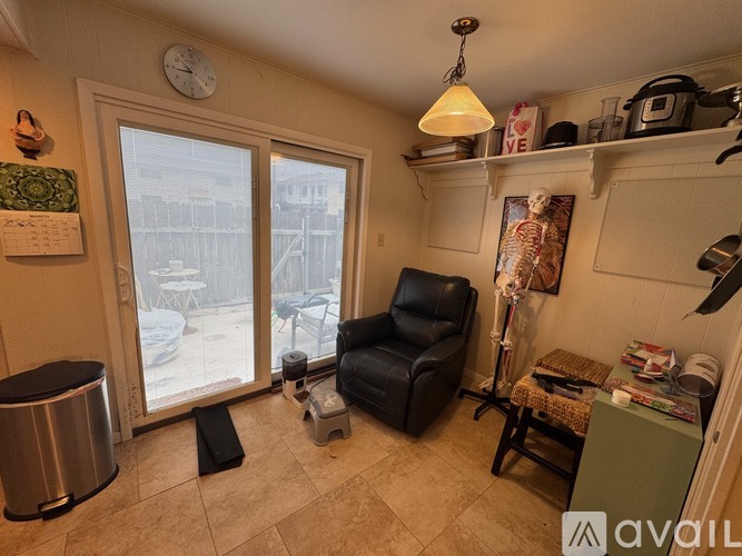 A living room with a black leather chair and a large window.
