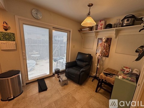 A living room with a black leather chair and a large window.