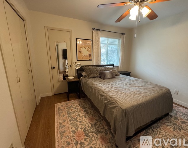 A bedroom with a bed, a nightstand, and a ceiling fan.
