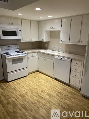 A kitchen with white cabinets and a wooden floor.