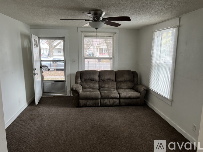 A living room with a brown sofa and a ceiling fan.