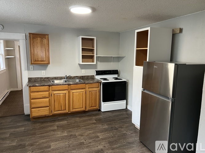 A kitchen with wooden cabinets and a stainless steel refrigerator.