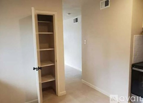 A white door with a black handle is open to a room with a white wall and a light switch.