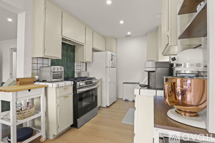 A modern kitchen with white cabinets and a copper pot on the stove.