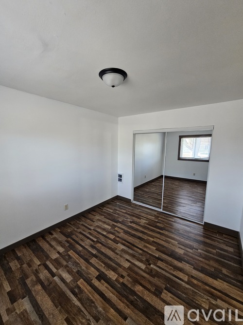 A room with wooden flooring and a white wall.
