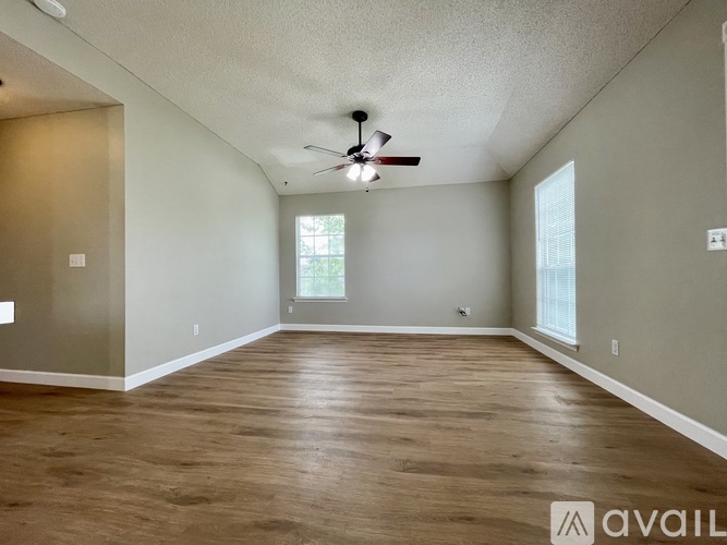A spacious room with a ceiling fan and wooden flooring.