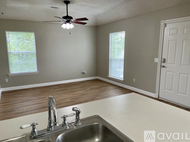 A kitchen with a sink, a ceiling fan, and a window.