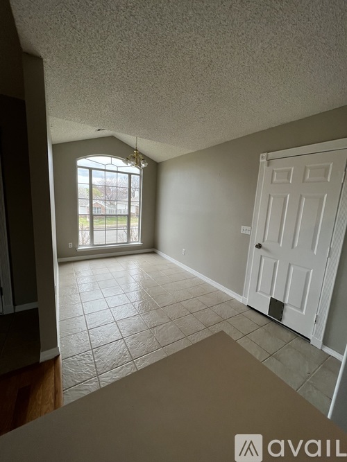 A room with a white door and a window with a view of a building outside.