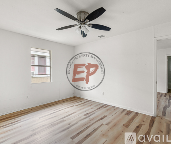 A room with a wooden floor and a ceiling fan with a logo on the wall.
