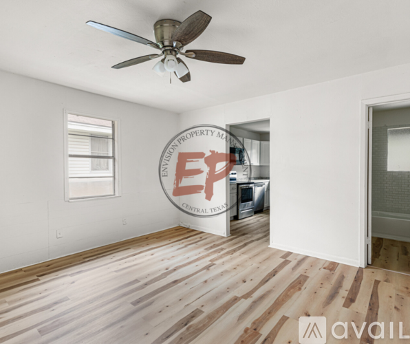 A room with a ceiling fan and wooden flooring.