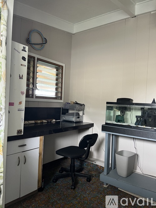 A small room with a desk and a fridge.