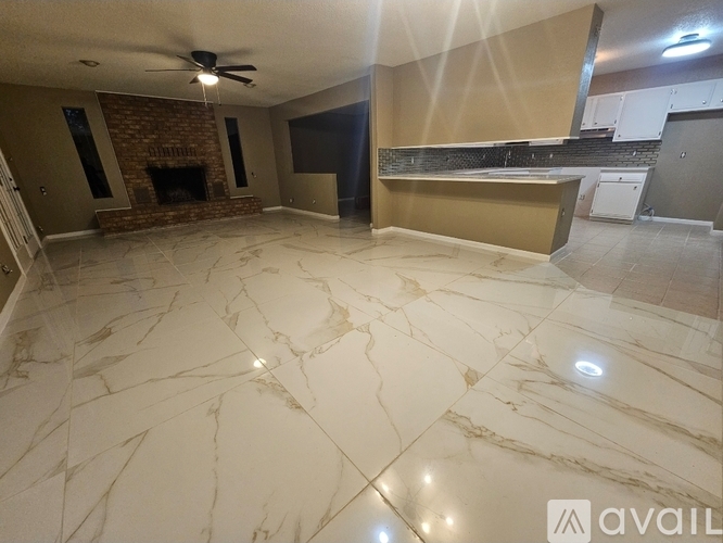 A spacious room with a marble floor and a fireplace.
