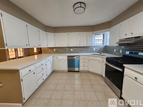 A kitchen with white cabinets and a tiled backsplash.