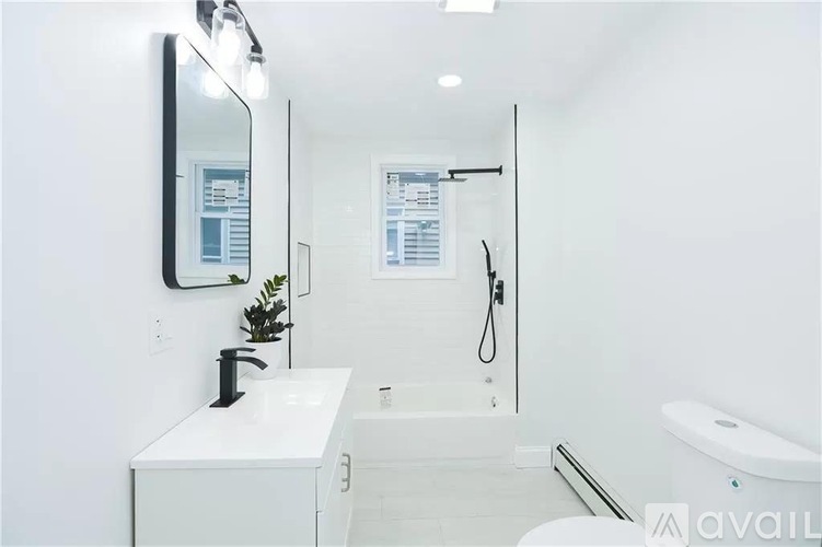 A white bathroom with a sink, mirror, and bathtub.