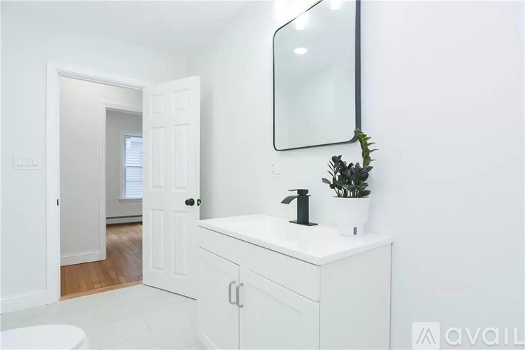 A white bathroom with a sink, mirror, and toilet.