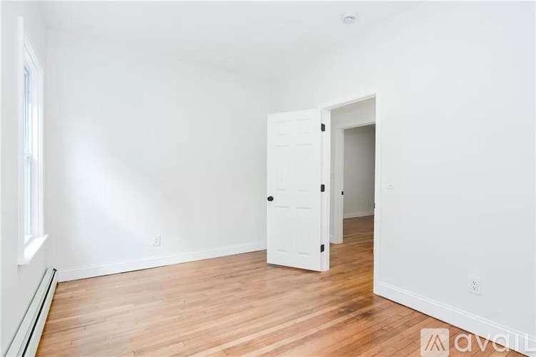 A room with a white door and wooden floor.