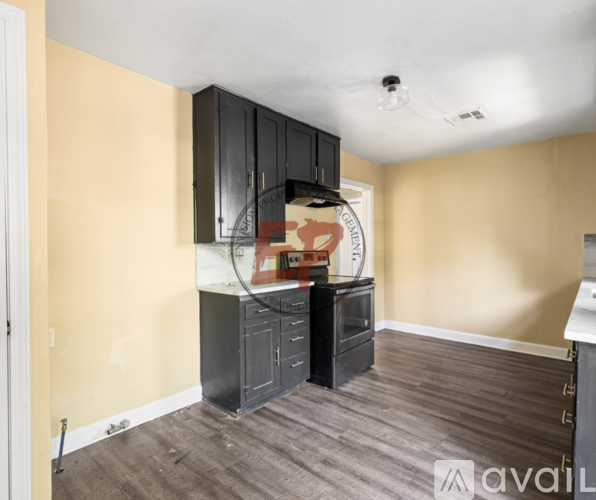 A kitchen area with black cabinets and a wooden floor.