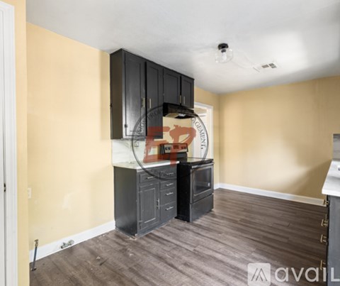 A kitchen area with black cabinets and a wooden floor.