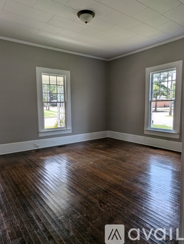 A room with wooden floors and two windows.