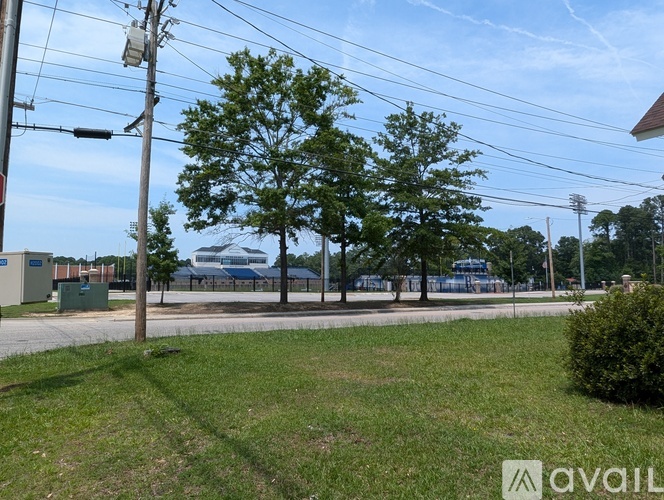 A grassy area with trees and a building in the distance.