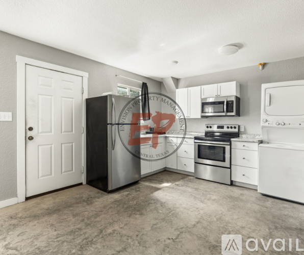 A kitchen with a black fridge, white cabinets, and a white door.
